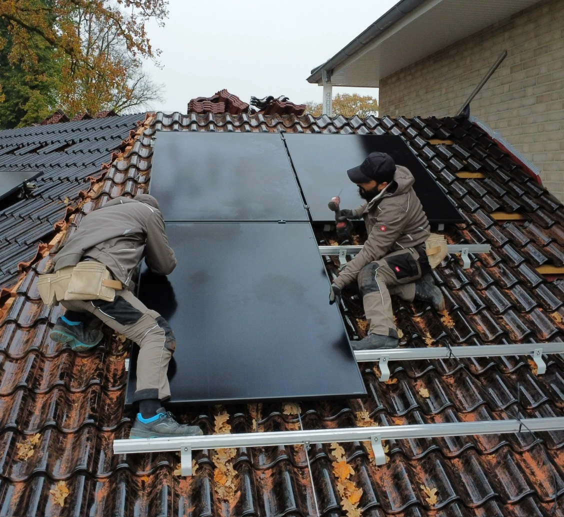 Handwerker installieren eine Solaranlage auf einem Dach.